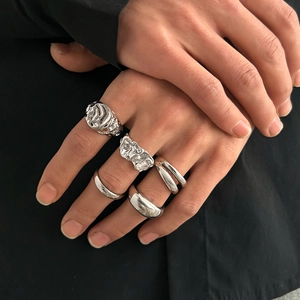 Detail of silver liquid metal rings set with irregular texture on male fingers