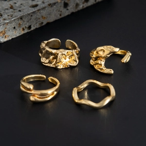 Set mit vier goldenen Ringen im Industrial-Stil mit Lava-Textur auf dunklem Hintergrund