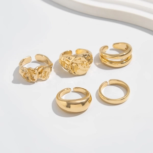 Detailed view of 5-piece gold liquid metal ring set with textured hammered and smooth designs