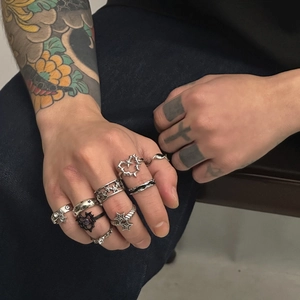 Nahaufnahme von Punk-Silberringen mit Herz-Dornen und Sternen an einer tätowierten Hand