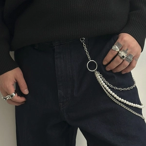 Detail of hip hop trouser chain with pearls and silver rings on denim pants