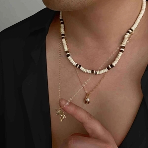 Detailopname van gelaagde kralenketting met palmboom en schelphangers in tropische stijl