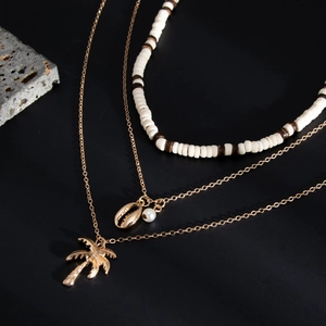 Detailweergave van de gelaagde kralenketting met kokosnootboom- en zeeschelp hangers