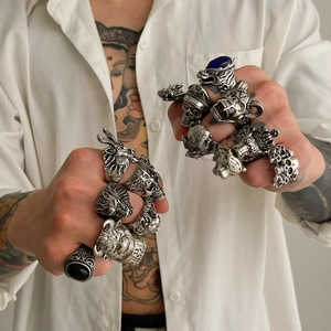 Gros plan de bagues punk vintage aux motifs de crâne portées sur des mains tatouées
