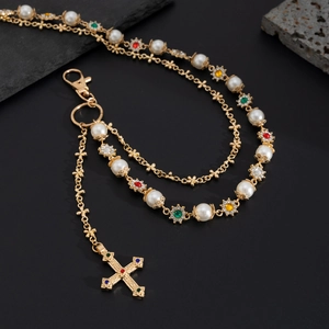 Detailed macro of gold chain with pearls, colorful gems, and a cross pendant accessory