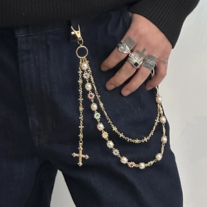 Detail showing gold multi-layer pearl pants chain with cross pendant and colorful gems
