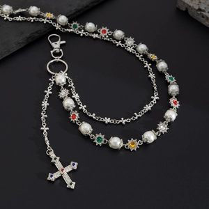 Detailed view of multilayer trousers chain with pearls and cross pendant with gemstones