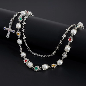 Detail of silver chain with cross pendant featuring pearls and colorful gemstones