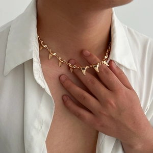 Golden alloy shark tooth necklace worn by male model over white shirt lifestyle view