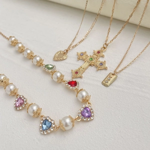 Detailliertes Set goldener Vintage-Halsketten mit bunten Herzsteinen und Kreuzanhänger