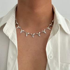 Detailed close-up of a silver shark tooth choker necklace worn on a person's neck