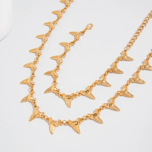 Detail of a gold shark fin pendant necklace with lobster clasp and textured surface