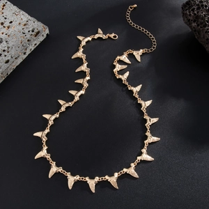 Detailed close-up of golden shark fin pendant necklace with intricate engraved stripes