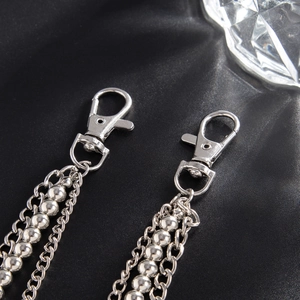 Detail of multi-layered silver bead and ring chain with polished lobster clasp on black fabric