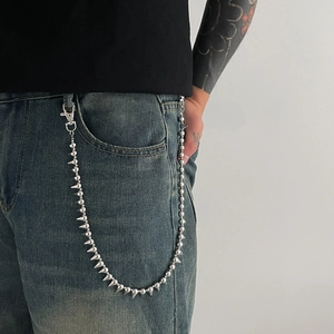 Punk style silver trouser chain with metal beads and spikes on blue jeans
