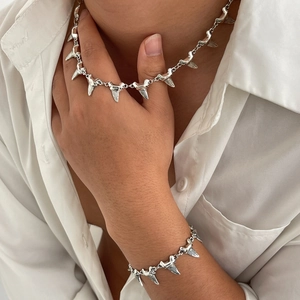 Silver shark tooth necklace and bracelet set shown on model with white shirt