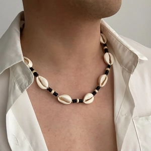 Detail van een schelpenketting met zwarte houten kralen op een herenmodel
