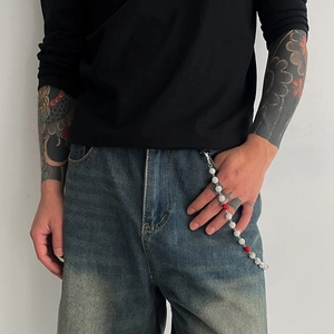 Détail de perles argentées gravées et accents rouges sur une chaîne de pantalon hip-hop