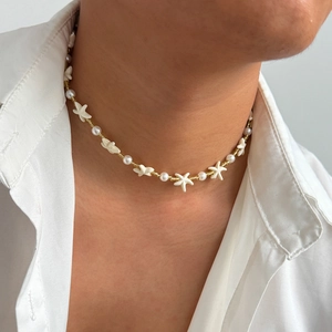 Detail shot of ocean style necklace featuring gold beads, starfish charms and pearls