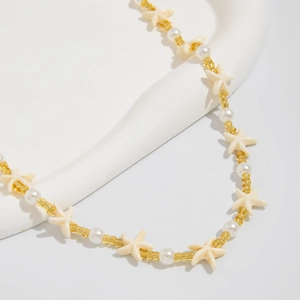 Close-up of beach necklace with white pearls, starfish charm and golden seed beads
