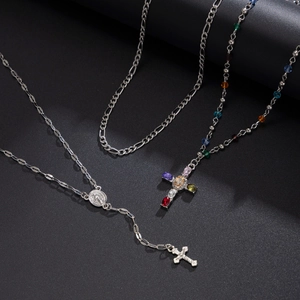 Dettaglio della collana con croce ghiacciata con gemme colorate e catena Figaro in acciaio