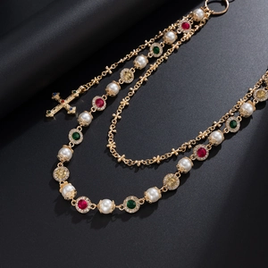 Close-up of multilayered gold chain featuring pearls, colorful gems, and a cross pendant