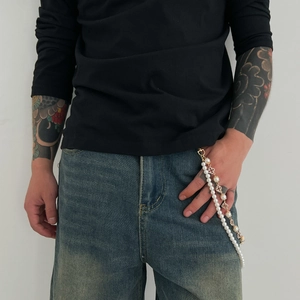 Detail view of double-layered hip-hop pant chain with faux pearls and golden floral charms