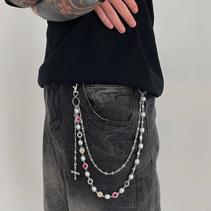 Detailed macro view of triple-layered metal pants chain with colorful rhinestones and cross