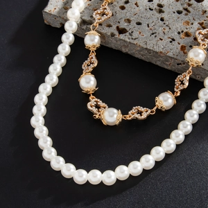 Detail of luxury pearl chain and gold floral pendant with rhinestones on stone background