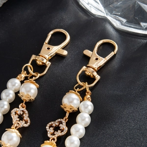 Detail of hip hop pearl pant chain with gold clover charms and sparkling crystals