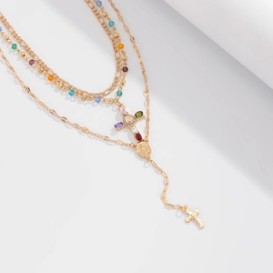Dettaglio collana a strati dorata con perle colorate e pendente a croce decorato