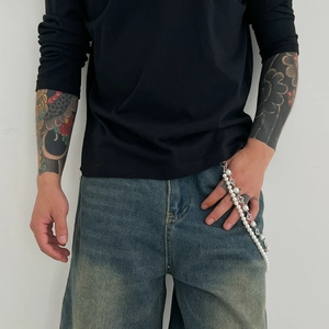 Detailed close-up of faux pearl and silver metal hip-hop pants chain on denim pocket