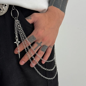 Detail of silver triple-layered metal pant chain with a star-cross pendant on denim jeans
