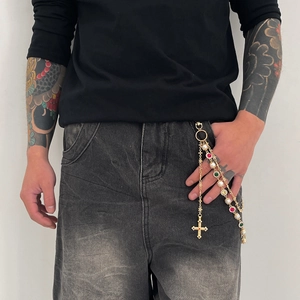 Close-up of golden hip-hop waist chain with colorful gemstones and cross pendant