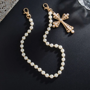 Detail of pearl trousers chain with ornate gold cross pendant and lobster clasps