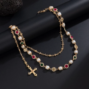 Detail of baroque gold chain with pearls, colorful gems, and a cross pendant charm