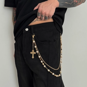 Detail of hip hop trouser chain with golden layers, pearls, and cross pendant accessory