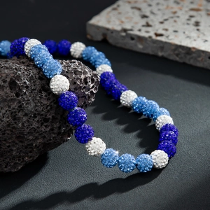 Close-up of blue and white disco ball rhinestone beads on natural black volcanic rock