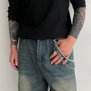 Detail of multi-layer turquoise beaded waist chain with silver coin pendant on denim