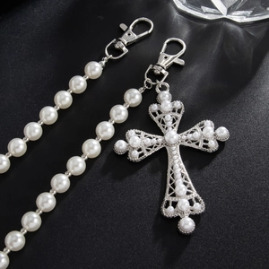 Detailed close-up of hip-hop trouser chain with white pearls and gothic cross pendant