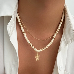 Detail of layered gold chain and beaded necklace featuring a textured starfish pendant