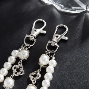 Detailed close-up of white faux pearl pants chain with sparkling clover flower charms