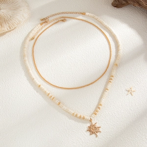 Detail of bohemian coconut shell beaded necklace with sun pendant and gold chain layering