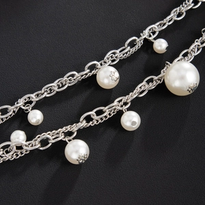 Macro shot of silver dual-strand chain with white pearls and vintage metal floral details