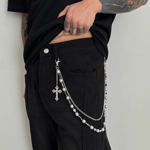 Detail of multi-layer silver trousers chain with pearl accents and a gothic cross pendant