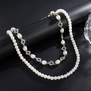 Close-up of double-layer necklace with white pearls and silver clover-shaped charms