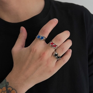 Close-up of three overlapping star rings in red, blue, and black enamel on a finger