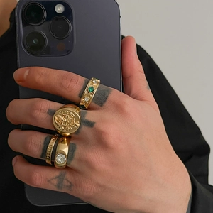 Makroaufnahme von goldenem Hip-Hop Ring-Set mit grünen Edelsteinen und Gravur-Siegeln