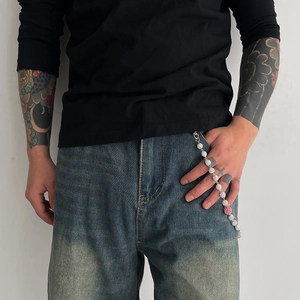 Détail d'une chaîne de pantalon à billes argentées avec perle rose sur un jean