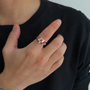 Detail of hand wearing silver metal ring with two red enamel pentagram stars on finger